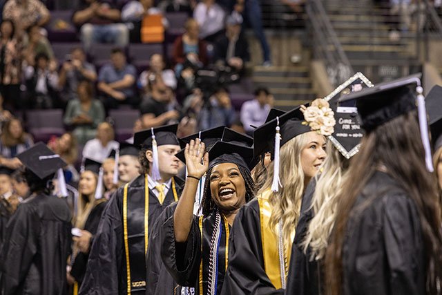 UCCS graduate waving at Commencement
